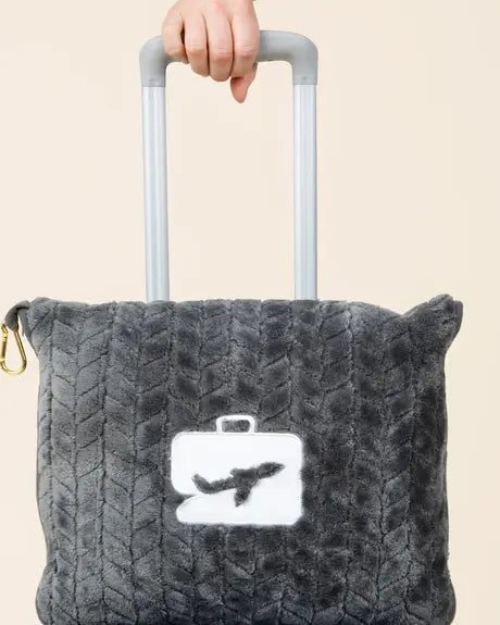 Hand on a suitcase handle with the EverSnug pillow clipped to the luggage