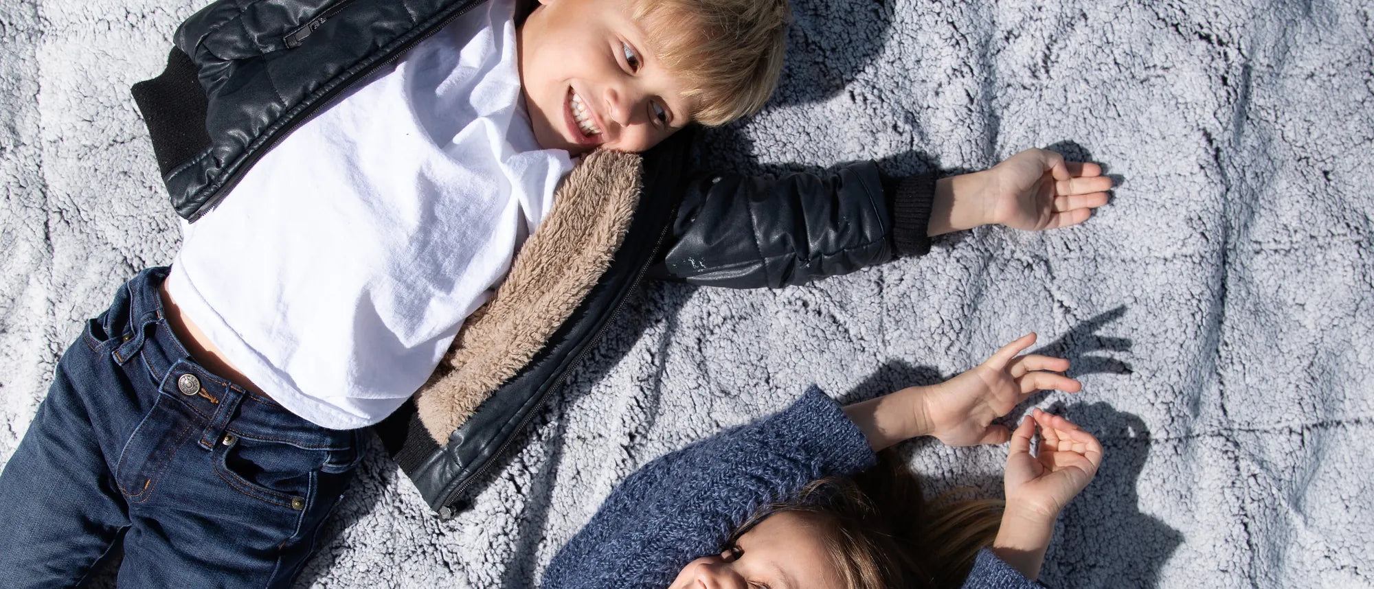 Two children relaxing together on a soft grey EverSnug blanket
